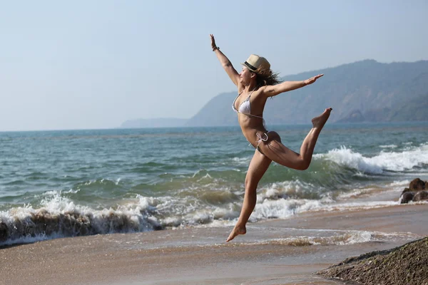 mutlu kız sahilde atlayarak, sportif sağlıklı seksi vücut uyacak bir bikini.