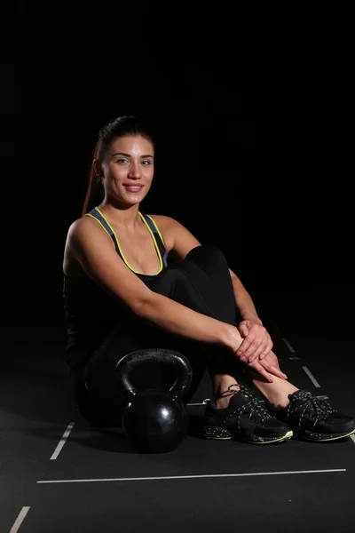 Leende ung Fitness kvinna, sitter med en Kettlebell — Stockfoto