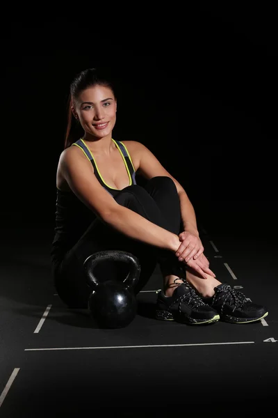 Leende ung Fitness kvinna, sitter med en Kettlebell — Stockfoto