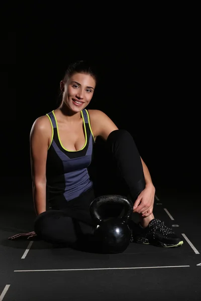 Leende ung Fitness kvinna, sitter med en Kettlebell — Stockfoto