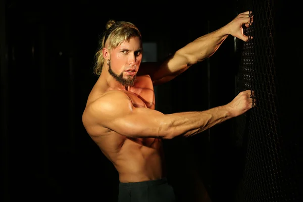 Close up young handsome muscular man near fence of grid — Stock Image Close up young handsome muscular man near fence of grid Stock Picture