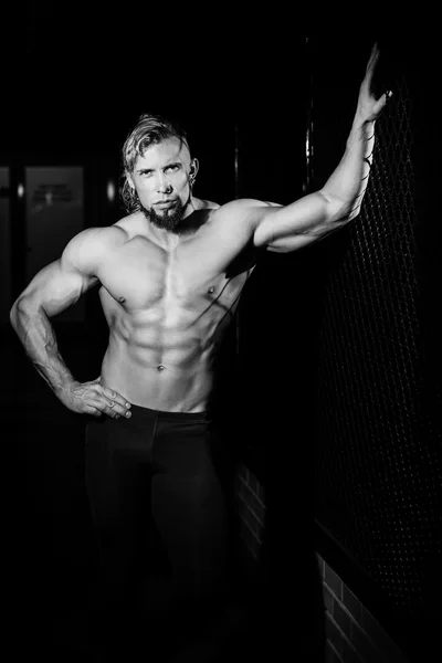 Young muscular man near fence grid. Black and white photo — Stockfoto