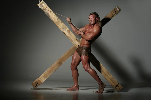 Sexual naked man, muscular, hands tied rope to wooden beams