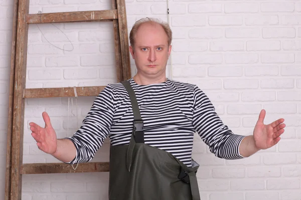 Fisherman shows hands the size of fish on white wall background. — ストック写真