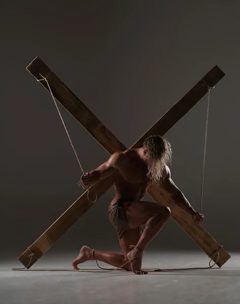 Сексуальный голый мужчина, мускулистый, руки связаны веревкой с деревянными балками — стоковое фото