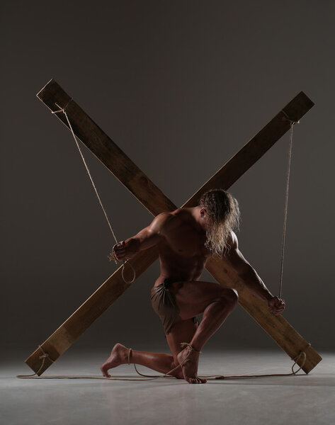 Sexual naked man, muscular, hands tied rope to wooden beams