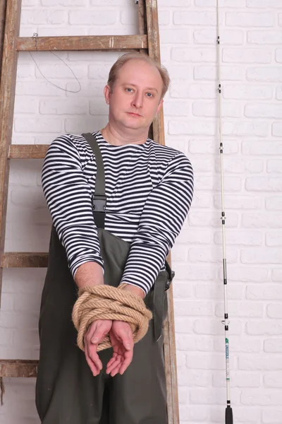 Fisherman stands near the ladder and hands tied rope — 스톡 사진