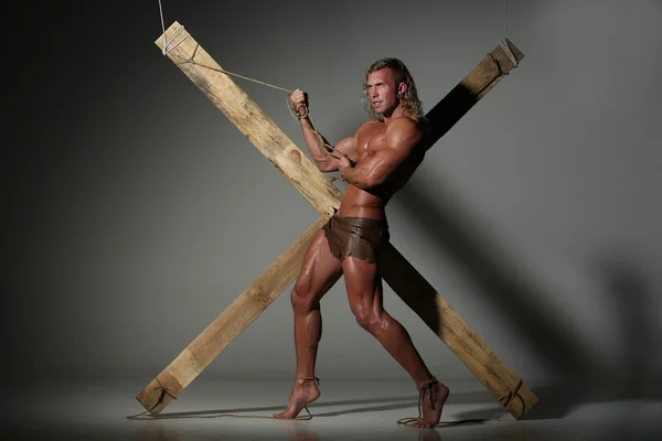 Sexual naked man, muscular, hands tied rope to wooden beams — Stock Photo, Image