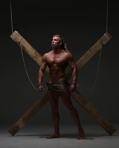 Sexual naked man, muscular, hands tied rope to wooden beams