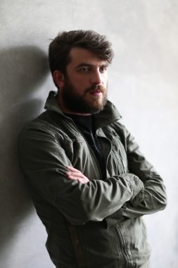 Haki ceketli adam çapraz elleriyle duvara yaslanmış. Kapat.up. Siyah