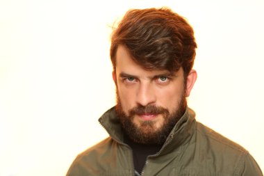 Sakallı adam ilginç bakışla haki ceket giymiş. Beyaz Close.up.