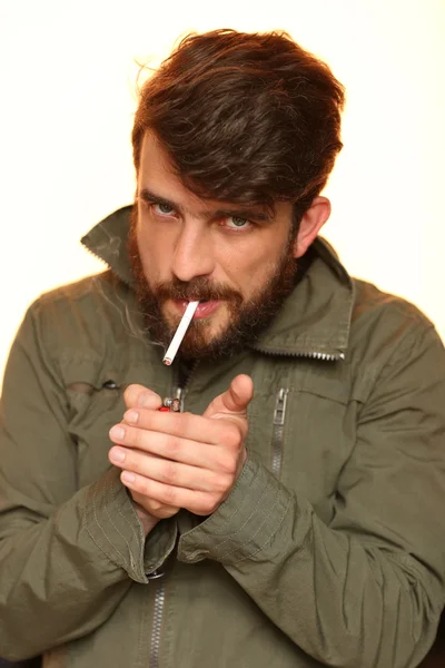 Un garçon barbu allume une cigarette. Ferme là. Blanc — Photo