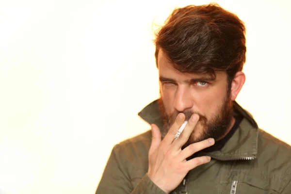 Muž v khaki bundě kouří cigaretu. Zblízka. Bílá — Stock fotografie