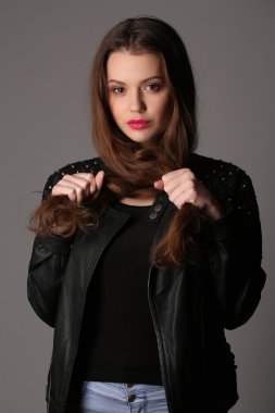 Teen saçını tutan bir çivili deri ceketli. Yakın çekim. Beyaz arka plan