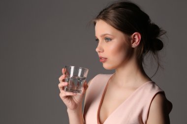 Bardak su kızla. Yakın çekim. Gri arka planı