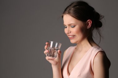 Kız bardak su ile poz. Yakın çekim. Gri arka planı