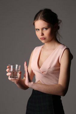 Pembe en iyi bardak su ile poz teen modeli. Yakın çekim. Gri arka planı