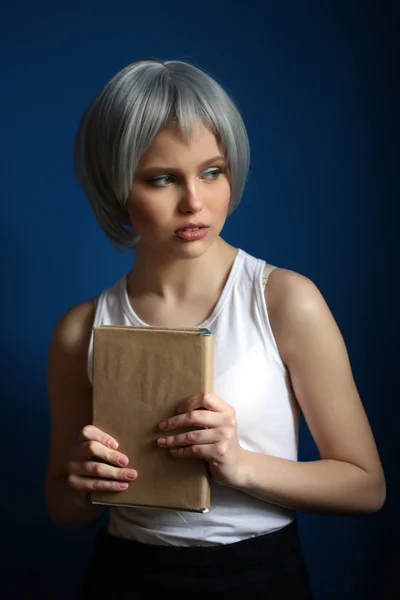 Mädchen mit silberner Perücke posiert mit Buch. Nahaufnahme. blauer Hintergrund — Stockfoto