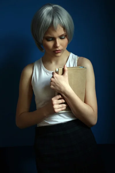 Model in silberner Perücke posiert mit Buch. Nahaufnahme. blauer Hintergrund — Stockfoto