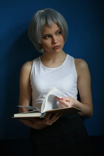 Teenager mit silbernen Haaren blättern durch das Buch. Nahaufnahme. blauer Hintergrund — Stockfoto