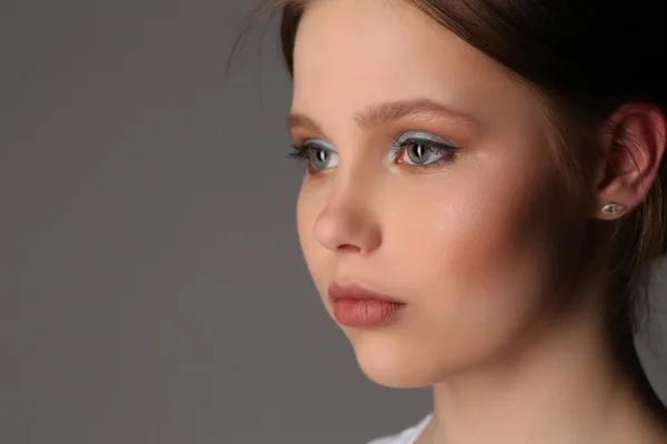 Mädchen mit Make-up schaut weg. Nahaufnahme. grauer Hintergrund — Stockfoto