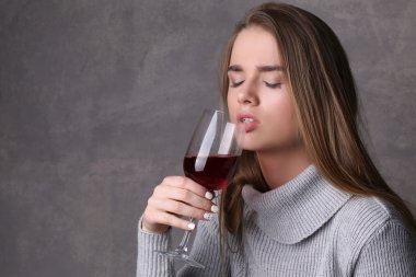 Gözleri kapalı bir kız şarap içiyor. Yakından kapatın. Gri arka plan