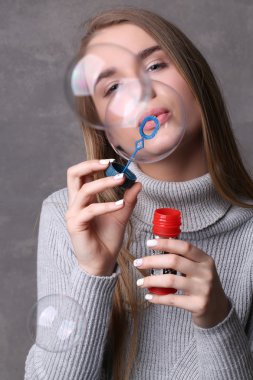 Jersey'li genç baloncuklar üflüyor. Yakından kapatın. Gri arka plan