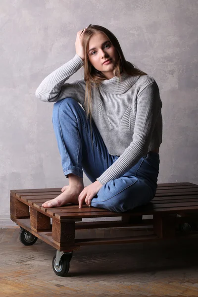 Mädchen im Pullover hält ihren Kopf. grauer Hintergrund — Stockfoto