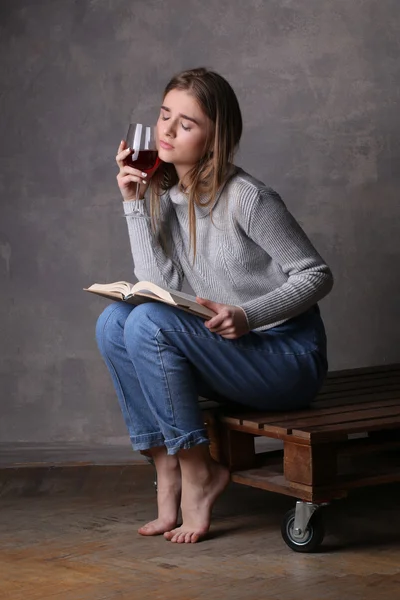 Siedzący model z książką i kieliszek wina. Szare tło — Zdjęcie stockowe