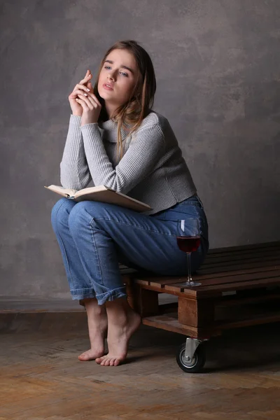 Modell som poserar med bok och glas vin. Grå bakgrund — Stockfoto