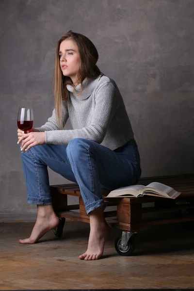 Model w swetrze i dżinsy trzymając Wineglass. Szare tło — Zdjęcie stockowe