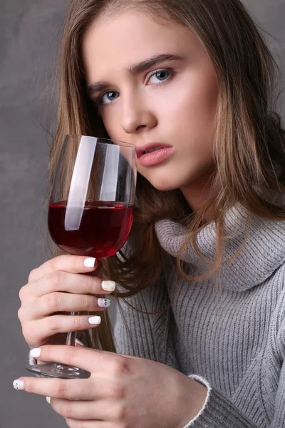Signora in maglione con in mano un bicchiere da vino. Chiudete. Fondo grigio — Foto Stock