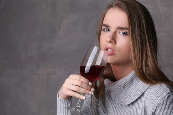 Flicka i tröja dricka vin. Närbild. Grå bakgrund — Stockfoto