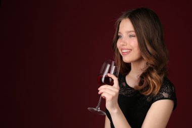 Şarap kadehiyle poz veren kız. Yakından kapatın. Koyu kırmızı arka plan