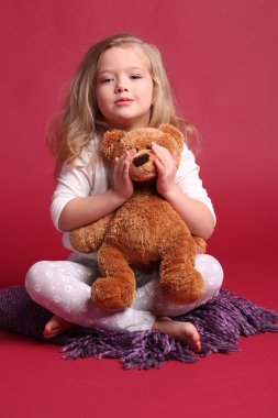 Pijamalı bebek ayı tutuyor. Kırmızı arka plan