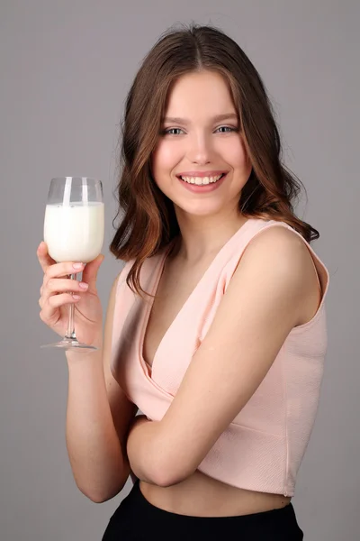 Mädchen posiert mit einem Glas Milch. Nahaufnahme. grauer Hintergrund — Stockfoto