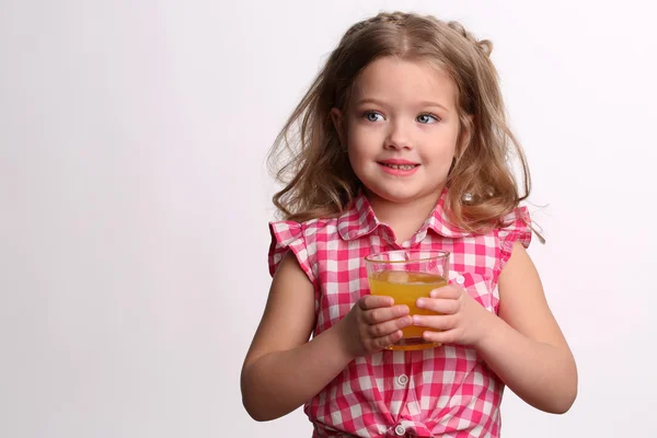 Little blondewith a glass of juice. Close up. White background Royalty Free Stock Photos