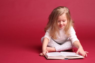 Pijamalı çocuk kitap okuyor. Kırmızı arka plan