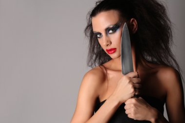 Bıçaklı ve vahşi saçlı model. Yakından kapatın. Gri arka plan