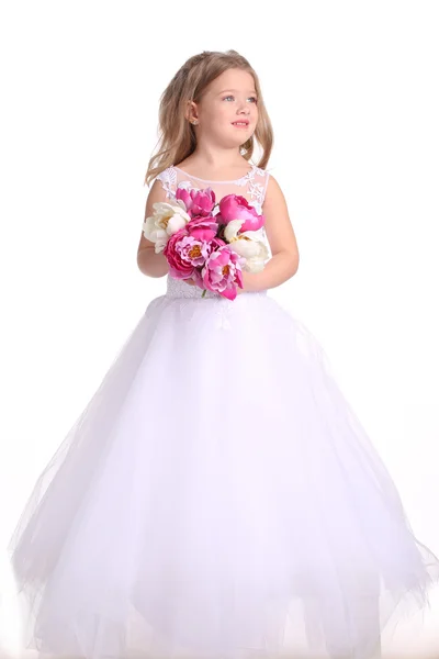 Dziecko w sukni ślubnej z kwiatami. Białe tło — Zdjęcie stockowe
