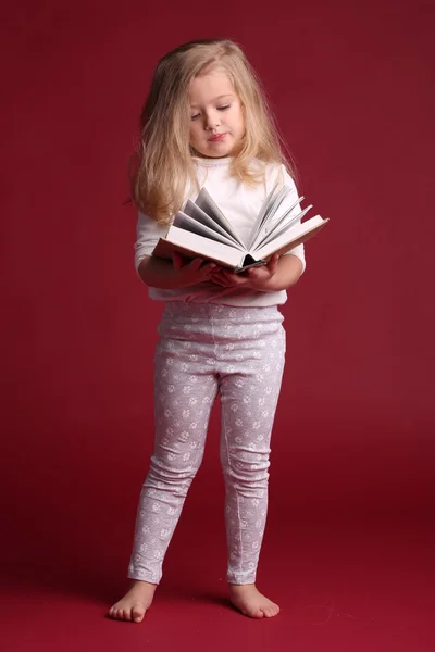 Retrato de una chica en el libro de lectura de ropa de dormir. Fondo rojo —  Fotos de Stock