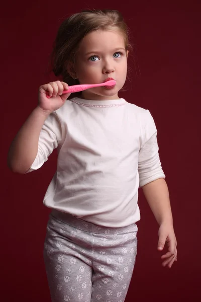 Kid i pyjamas borsta tänderna. Närbild. Röd bakgrund — Stockfoto