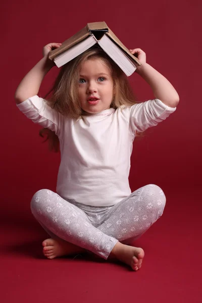 Lady w piżamie z książką na głowie. Czerwone tło — Zdjęcie stockowe