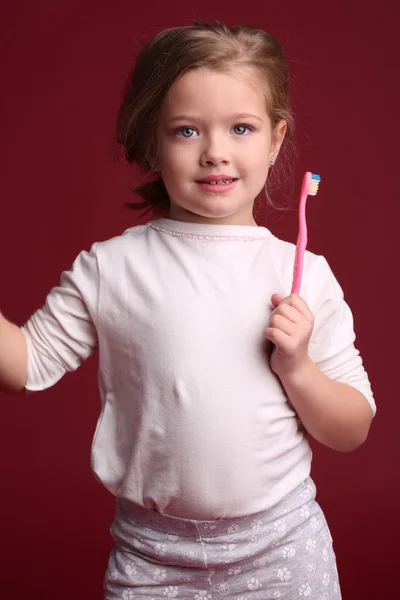 Liten flicka med tandborste. Närbild. Röd bakgrund — Stockfoto