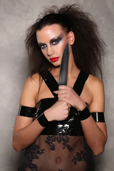Donna pericolosa con un coltello e capelli selvaggi. Chiudete. Sfondo grigio — Foto Stock
