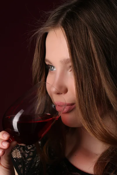 Flicka dricka alkohol. Närbild. Mörk röd bakgrund — Stockfoto