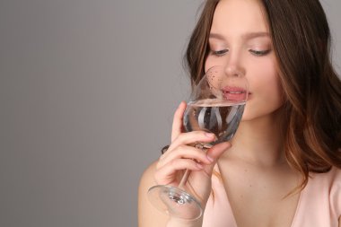 Genç bir bocal gelen su içme. Yakından kapatın. Gri arka plan