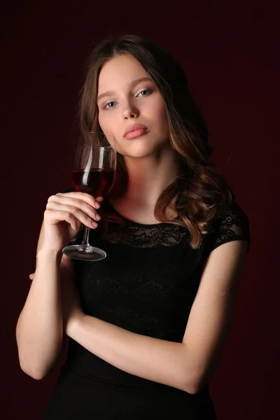Ritratto di ragazza con bicchiere da vino. Chiudete. sfondo rosso scuro — Foto Stock