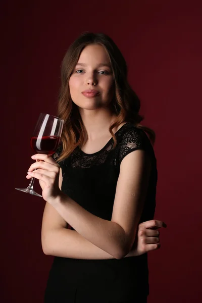 Portret modelu w czarnej sukni z winem. Z bliska. Ciemnoczerwone tło — Zdjęcie stockowe