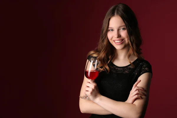Nastolatka z winem i skrzyżowanymi ramionami. Z bliska. Ciemnoczerwone tło — Zdjęcie stockowe